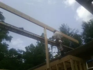 Carpenter setting a ridge beam over a new addition frame — Ice Dam Removal by Roofing Brothers in Southold
