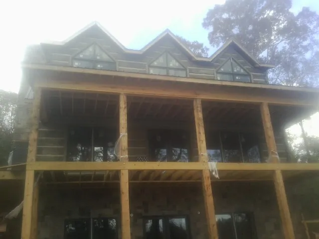 Dormers and porch framing on a large log home under construction — Roof Coating work by our crew in Southold