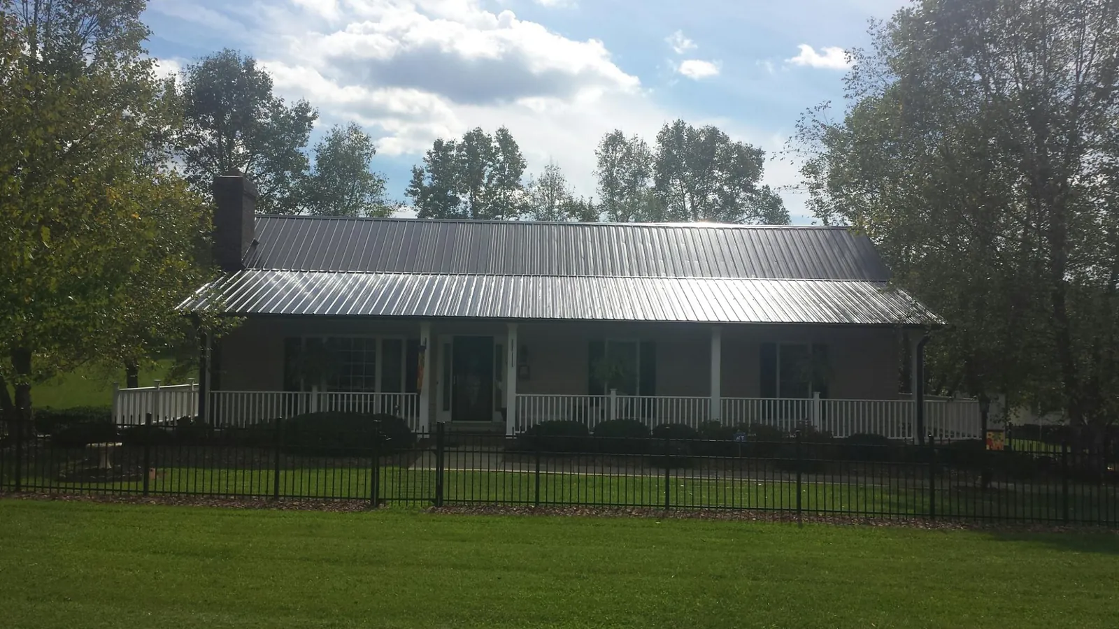 Gray metal roof on a brick ranch with a full width front porch — Gutter Guard Installation work by our crew in Southold