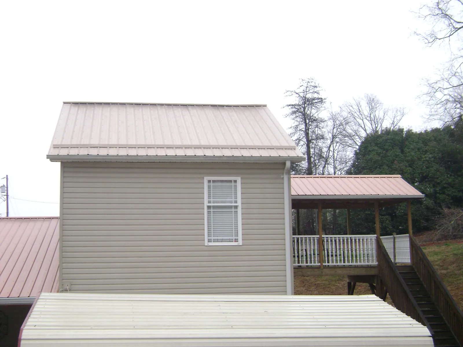 Tan metal roofs on a two story addition and attached porch, from a Roof Replacement job in Southold