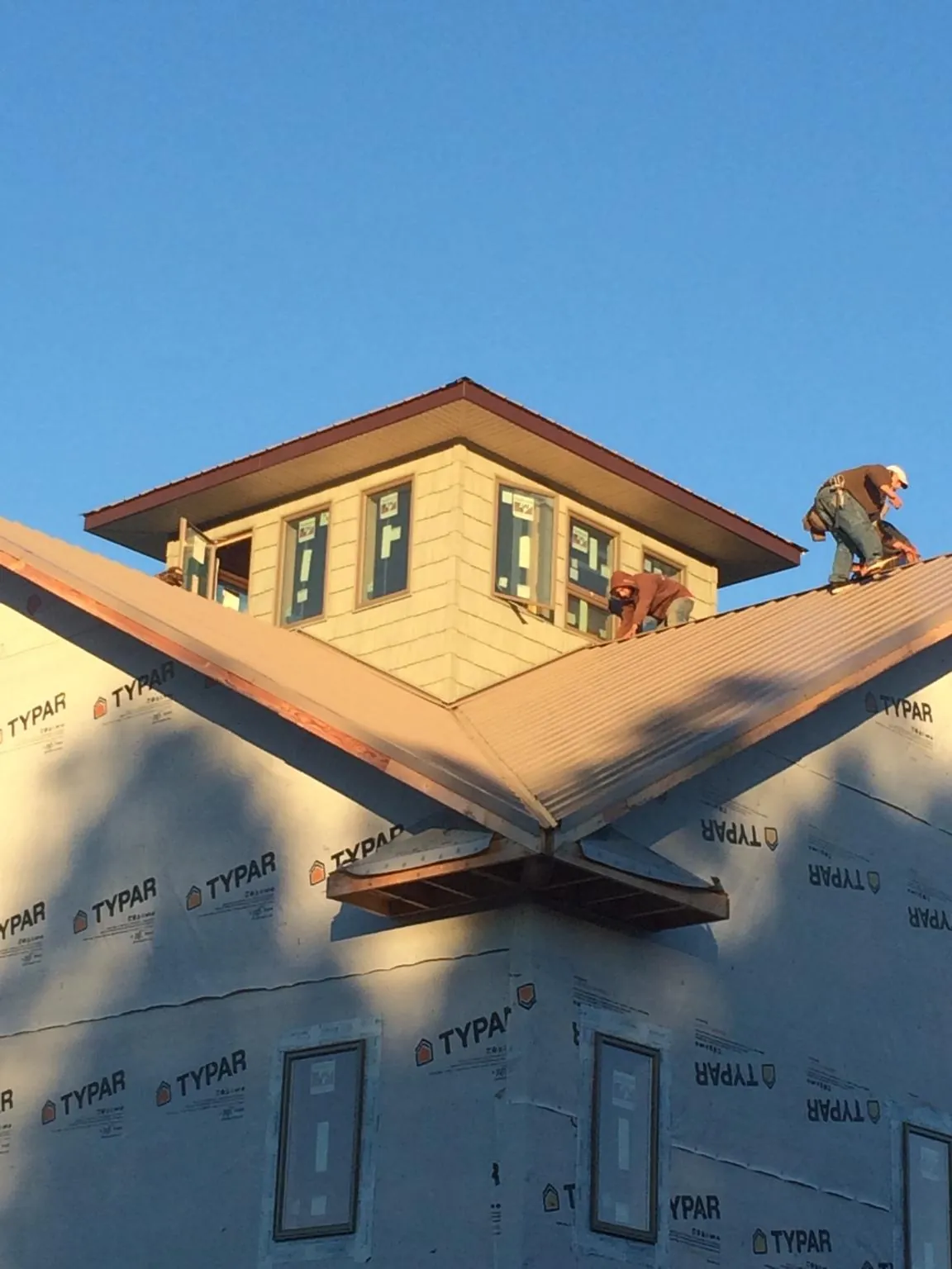 Roofers working around a rooftop cupola on a new metal roof at sunset — Roof Waterproofing in Southold by Roofing Brothers